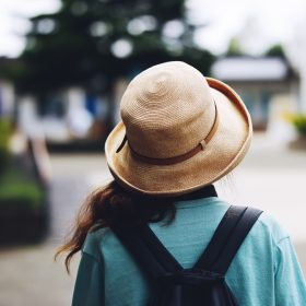 帽子を被って出かける女性の後ろ姿