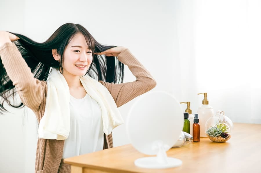鏡の前で髪を乾かす女性