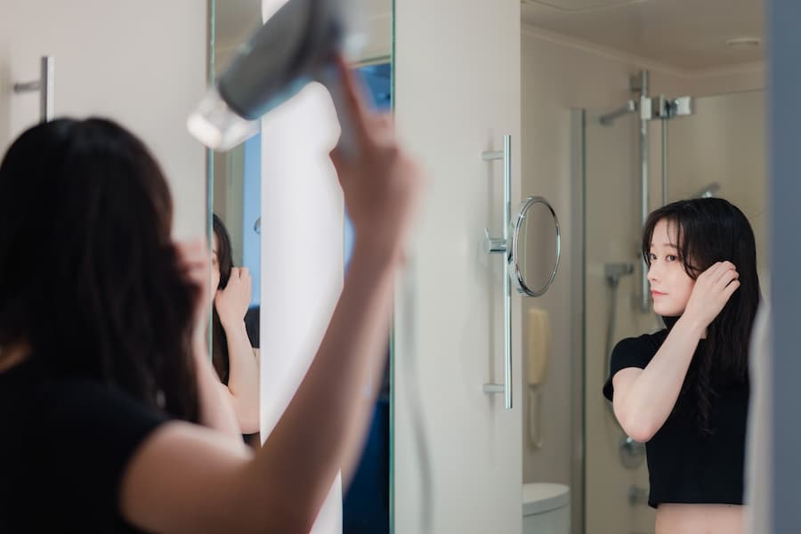 ドライヤーで髪を乾かす女性