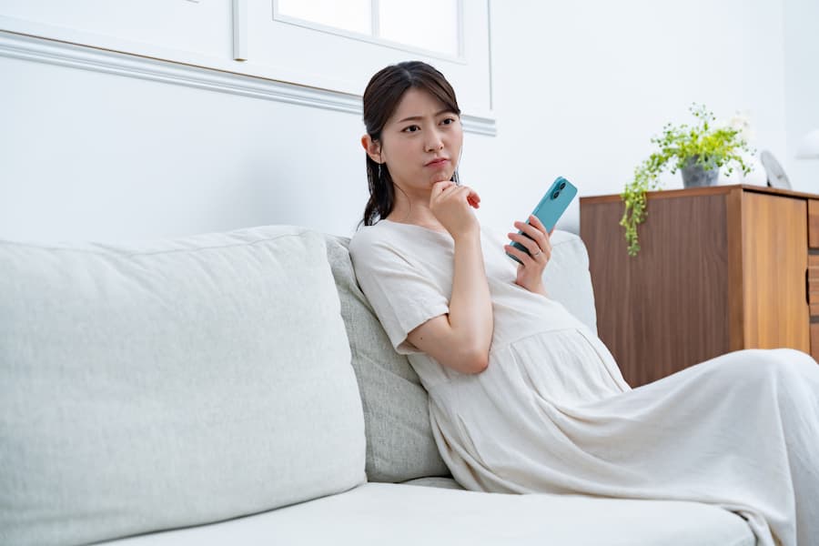ソファで携帯を持つ妊婦